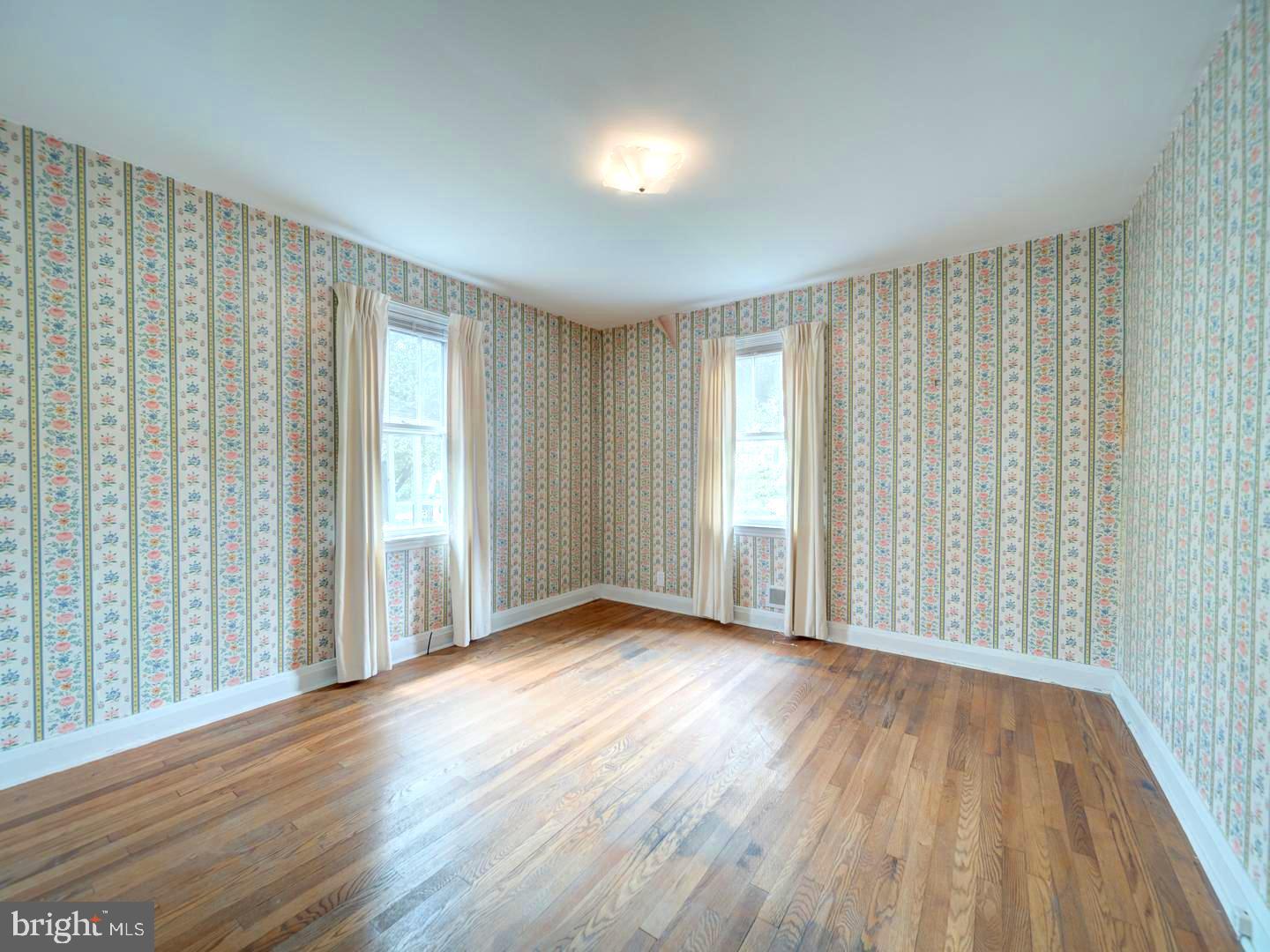 6505 Beechwood Road Baltimore, MD 21239 - Photo 19 of 46 an empty room with wooden floor and windows with curtains view