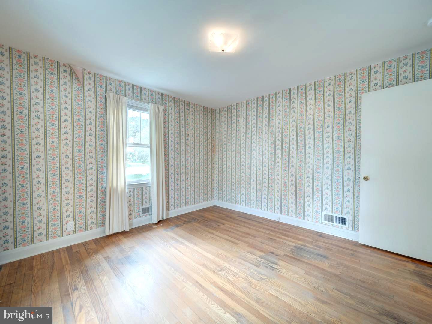 6505 Beechwood Road Baltimore, MD 21239 - Photo 20 of 46 an empty room with wooden floor and windows