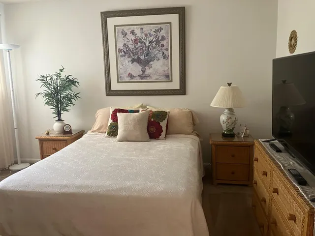 a bedroom with a bed and a potted plant on the dresser