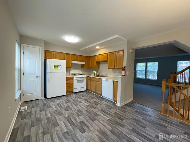 a kitchen with a refrigerator and wooden floor