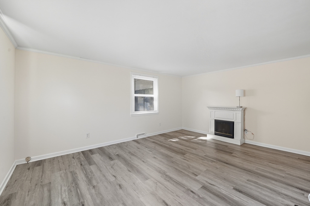 86 Talmadge Drive Springfield, MA 01118 - Photo 5 of 33 an empty room with wooden floor fireplace and windows