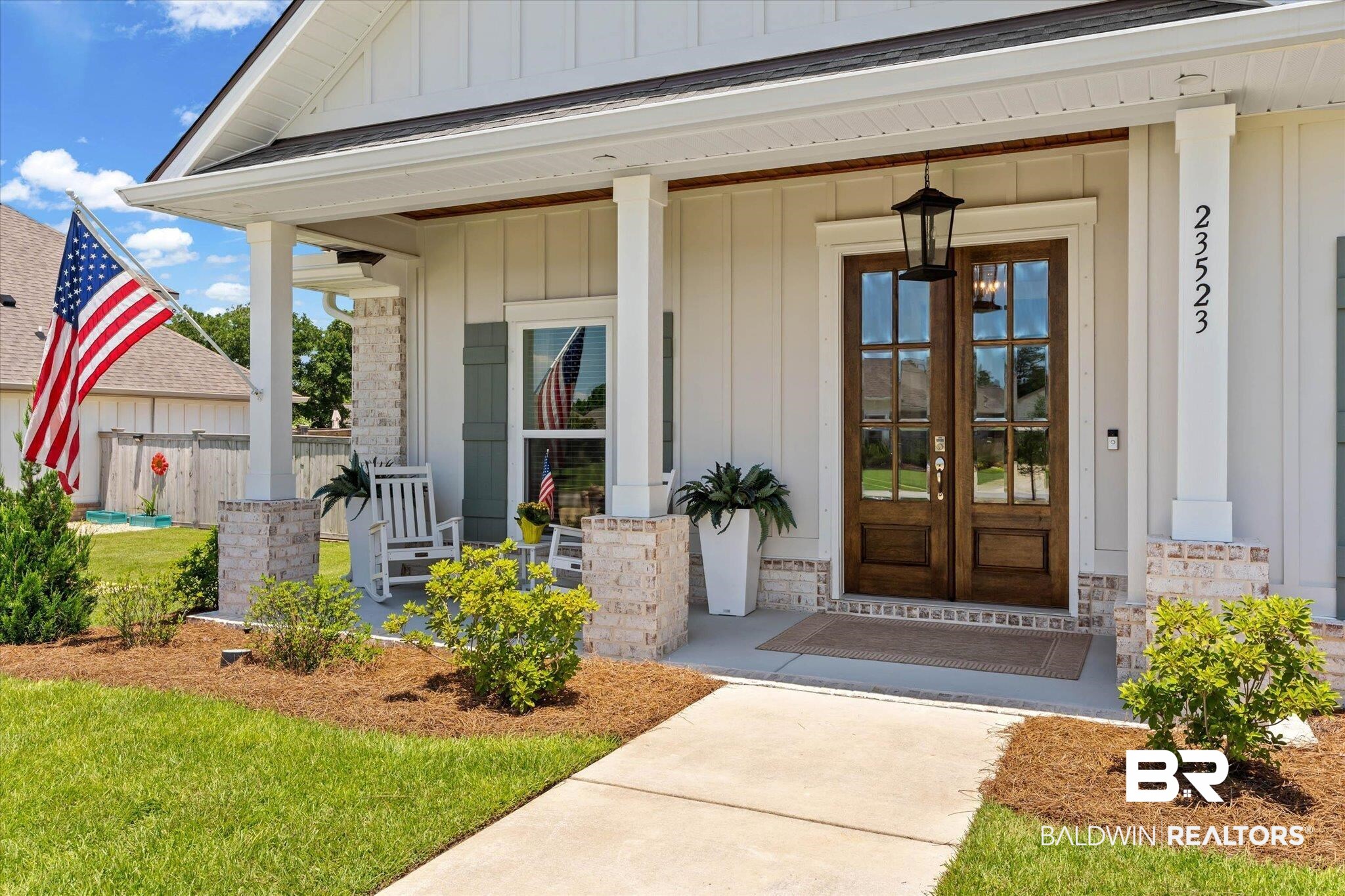 23523 Travis Stock Street Foley, AL 36535 - Photo 2 of 45 Inviting front porch featuring a pair of wood-finish French doors with glass inserts, board and batten siding, brick accents, and a concrete walkway