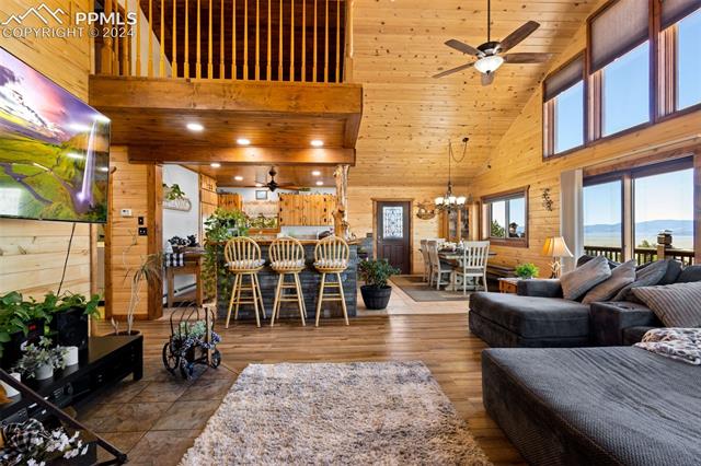 211 Yarnell Road Lake George, CO 80827 - Photo 12 of 50 Tiled living room with high vaulted ceiling, wood walls, a mountain view, and ceiling fan with notable chandelier