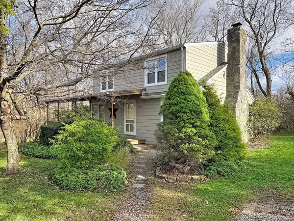 a backyard of a house with plants and large tree