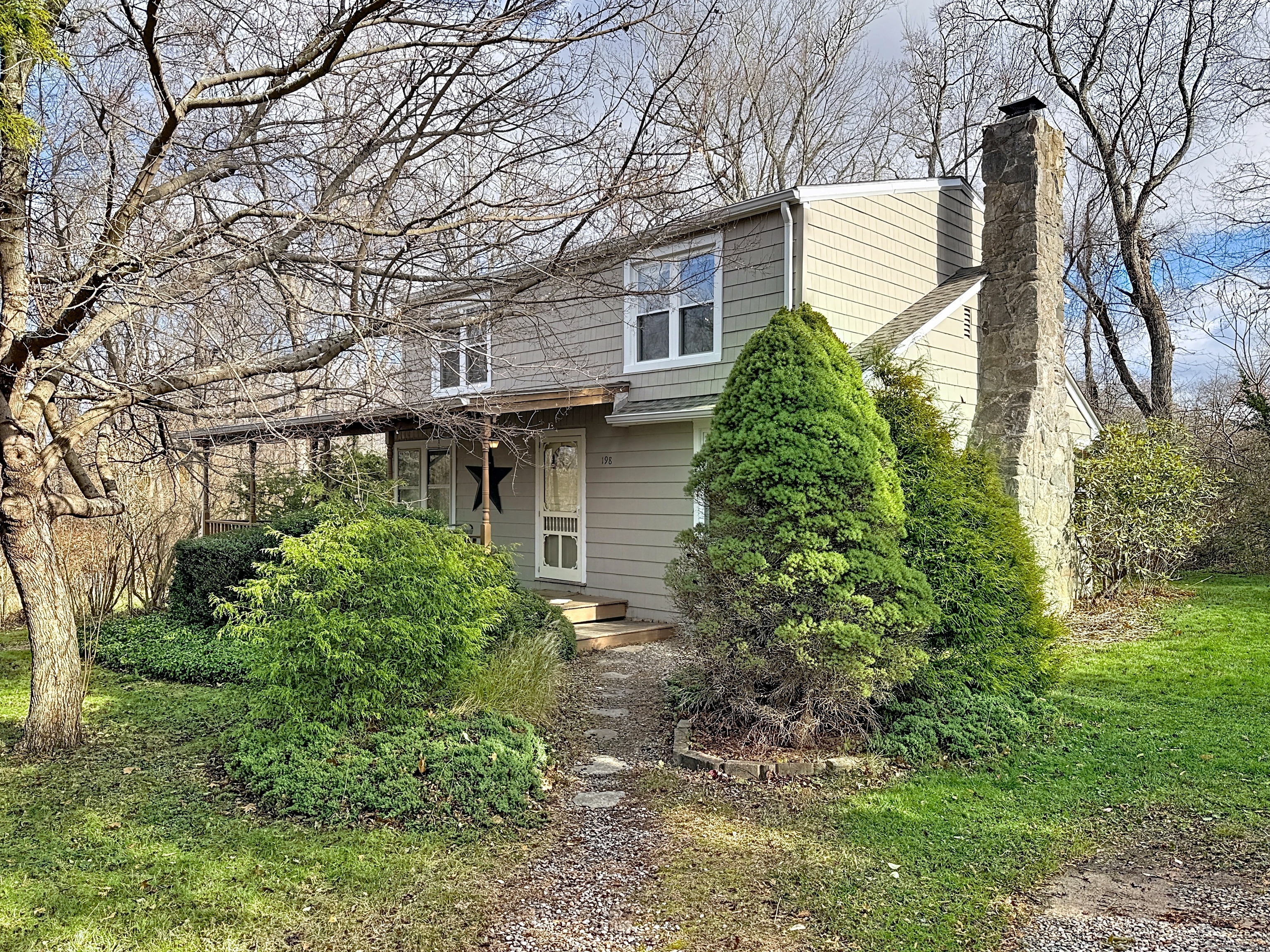 a backyard of a house with plants and large tree