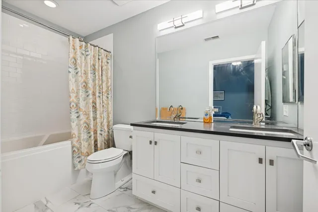 a bathroom with a granite countertop sink a toilet a mirror a bathtub and shower