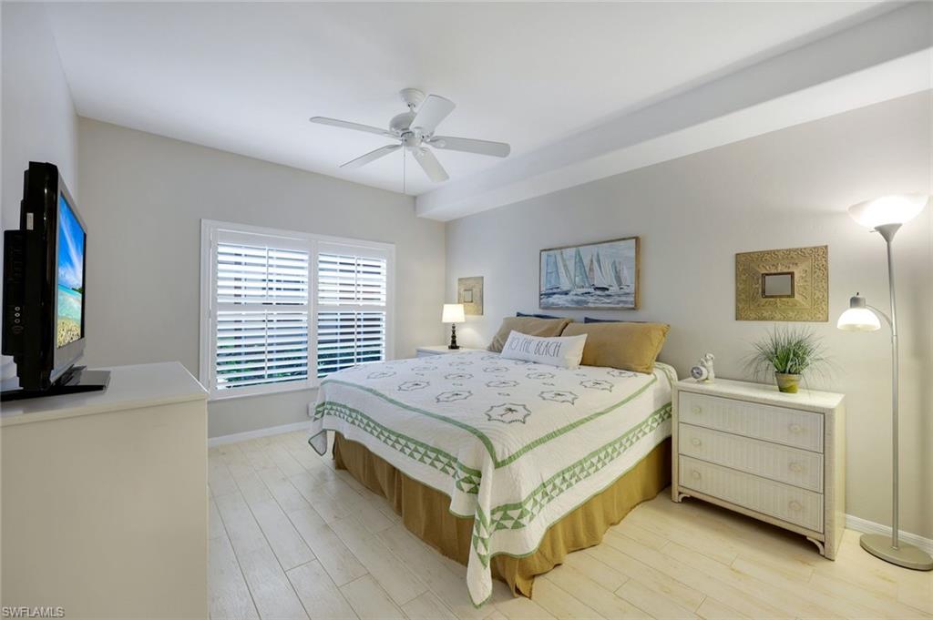 13201 Sherburne Circle, Unit 102 Bonita Springs, FL 34135 - Photo 11 of 22 a spacious bedroom with a bed and a chandelier