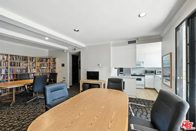 a kitchen with stainless steel appliances a stove a refrigerator a sink dishwasher and a dining table with wooden floor