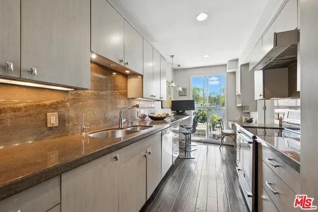 a kitchen with stainless steel appliances a sink dishwasher a stove top oven a refrigerator with wooden floors