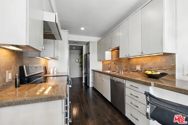a kitchen with stainless steel appliances granite countertop a sink a stove and a wooden floors