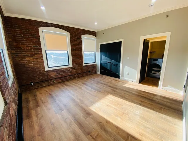 a view of an empty room with window and wooden floor