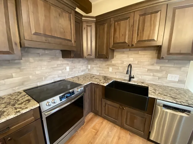 a kitchen with granite countertop a stove top oven microwave and cabinets