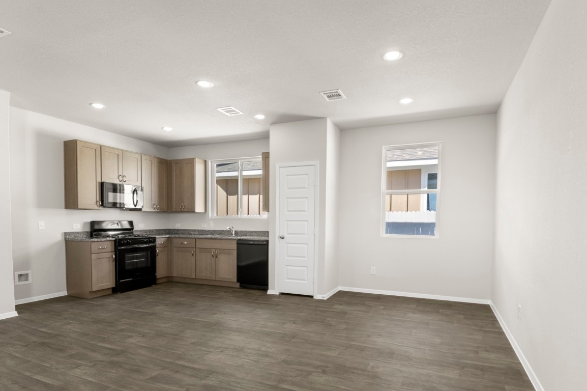 167 Daylily Drive Elgin, TX 78621 - Photo 14 of 29 a large kitchen with stainless steel appliances granite countertop a stove a sink a refrigerator and a refrigerator