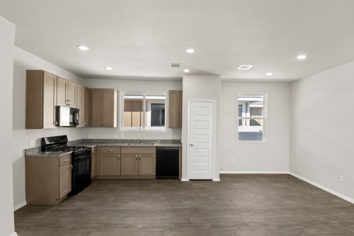 167 Daylily Drive Elgin, TX 78621 - Photo 16 of 29 a large kitchen with stainless steel appliances granite countertop a sink and a stove top oven