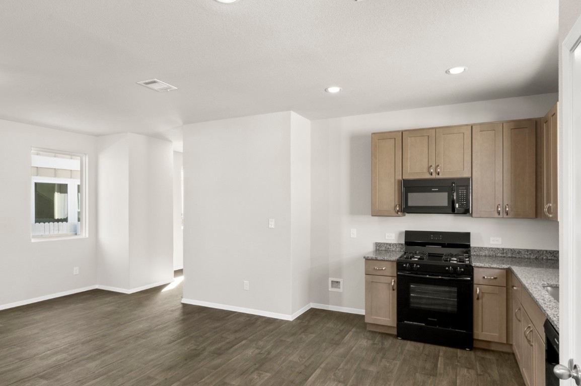 167 Daylily Drive Elgin, TX 78621 - Photo 18 of 29 a kitchen with granite countertop a stove and a refrigerator