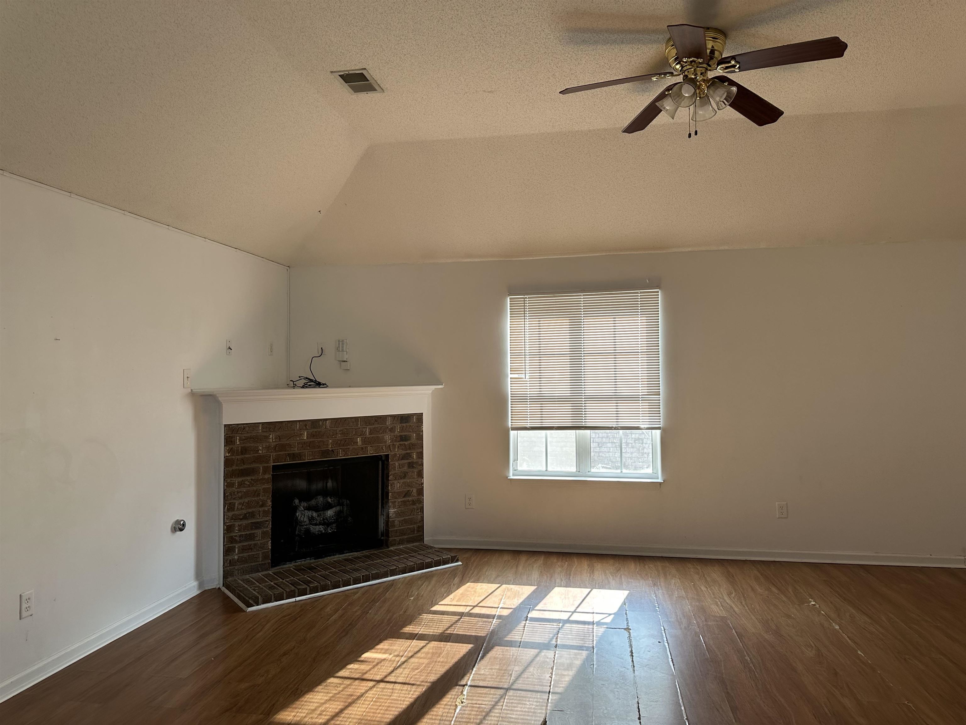 Living space featuring wood-finish flooring and a vaulted ceiling with a ceiling fan