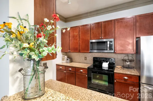 a kitchen with stainless steel appliances kitchen island granite countertop a sink a stove and a microwave