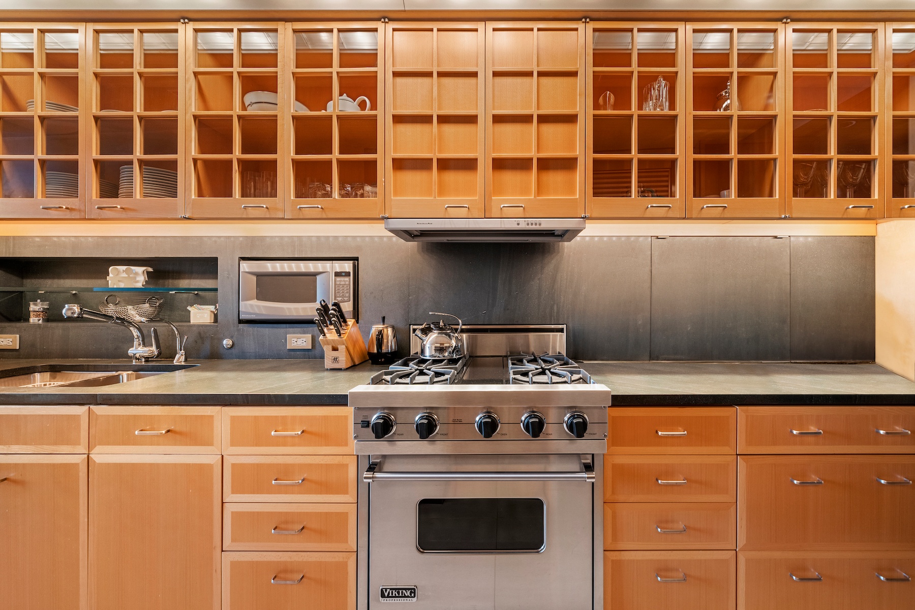 781 5th Avenue, Unit 2001 Manhattan, NY 10022 - Photo 16 of 19 a kitchen with granite countertop a stove a sink and a microwave