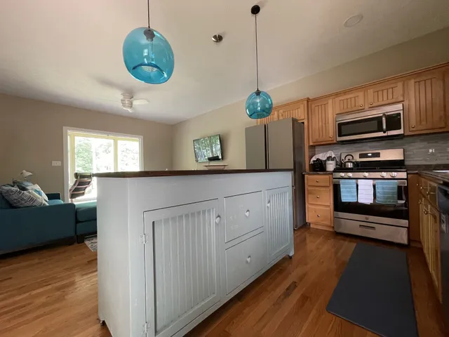 a kitchen with stainless steel appliances granite countertop a stove a sink dishwasher a refrigerator and a fireplace with wooden floor