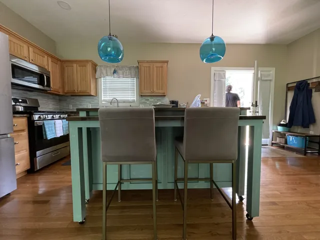 a kitchen with stainless steel appliances granite countertop a stove top oven a dining table and chairs with wooden floor