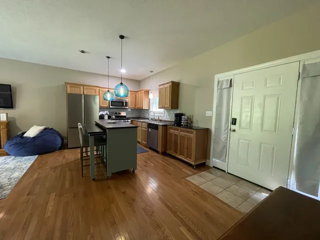 a kitchen with stainless steel appliances granite countertop a stove top oven a sink dishwasher a refrigerator and white cabinets with wooden floor