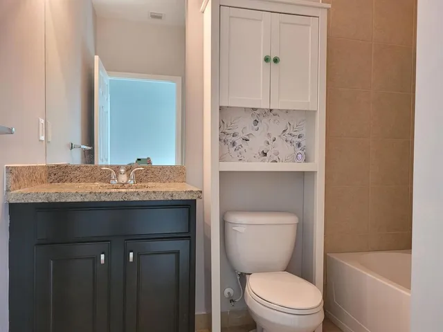a bathroom with a granite countertop toilet a sink and a mirror