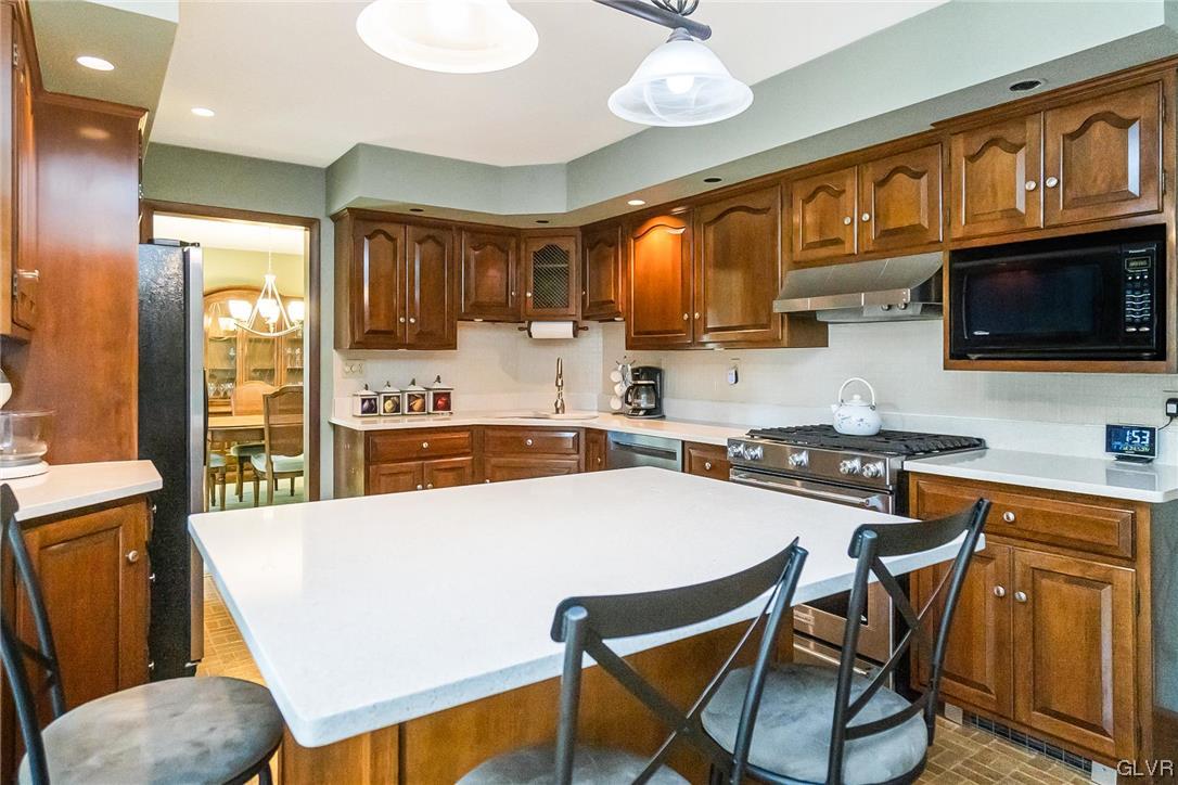 7116 Linden Road Lower Macungie Township, PA 18062 - Photo 8 of 41 a kitchen with stainless steel appliances granite countertop a stove top oven a sink a dining table and chairs with wooden floor