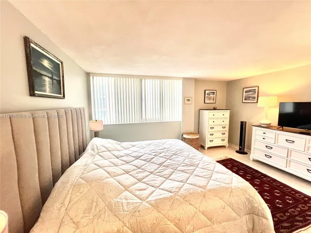 a spacious bedroom with a bed and a flat screen tv