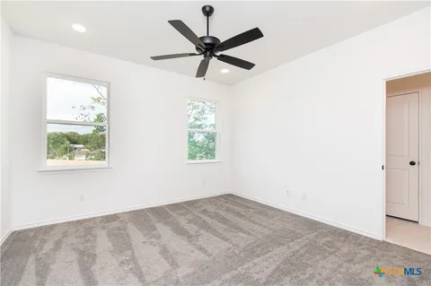an empty room with ceiling fan and window