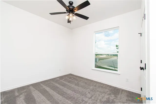 an empty room with a window and a fan