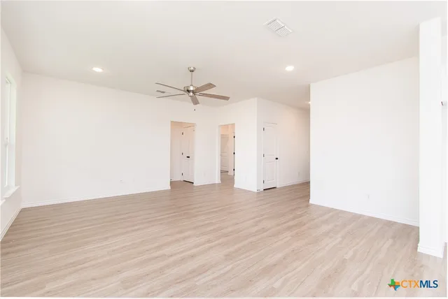 an empty room with wooden floor and ceiling fan