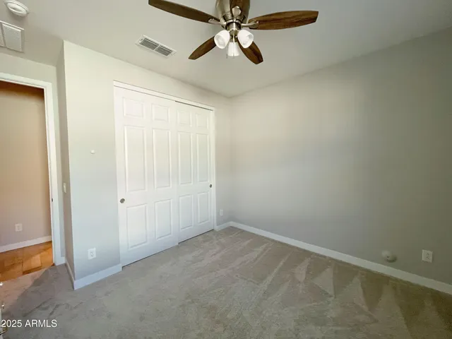 an empty room with closet and a chandelier fan