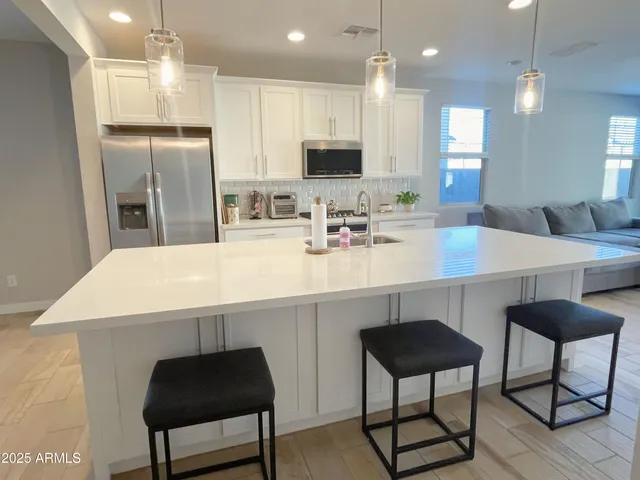 a kitchen with stainless steel appliances a dining table chairs refrigerator and microwave