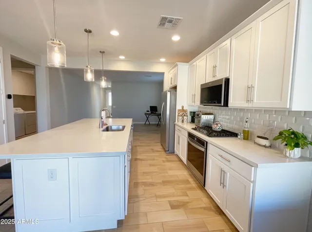 a large kitchen with kitchen island a sink stainless steel appliances and cabinets