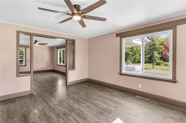a view of an empty room with window and wooden floor