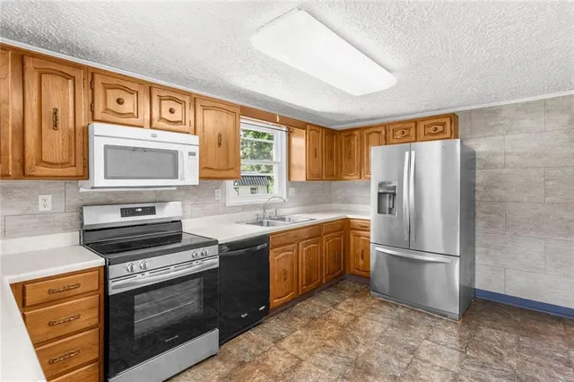 a kitchen with stainless steel appliances granite countertop a refrigerator stove and sink