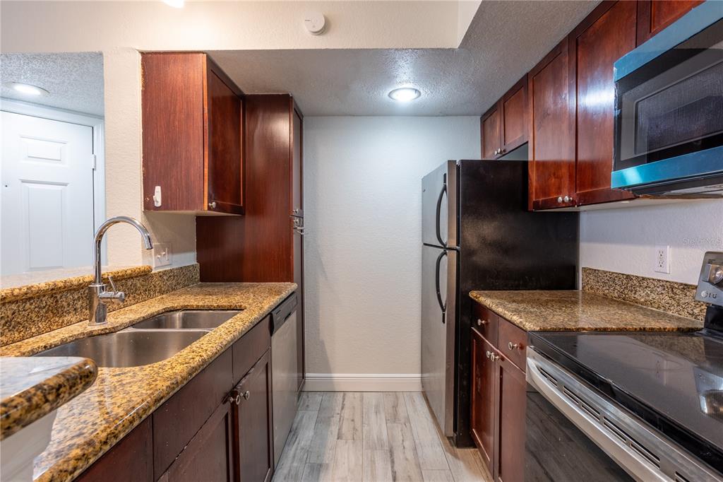5156 Conroy Road, Unit 16 Orlando, FL 32811 - Photo 7 of 16 a kitchen with stainless steel appliances granite countertop a sink stove and refrigerator