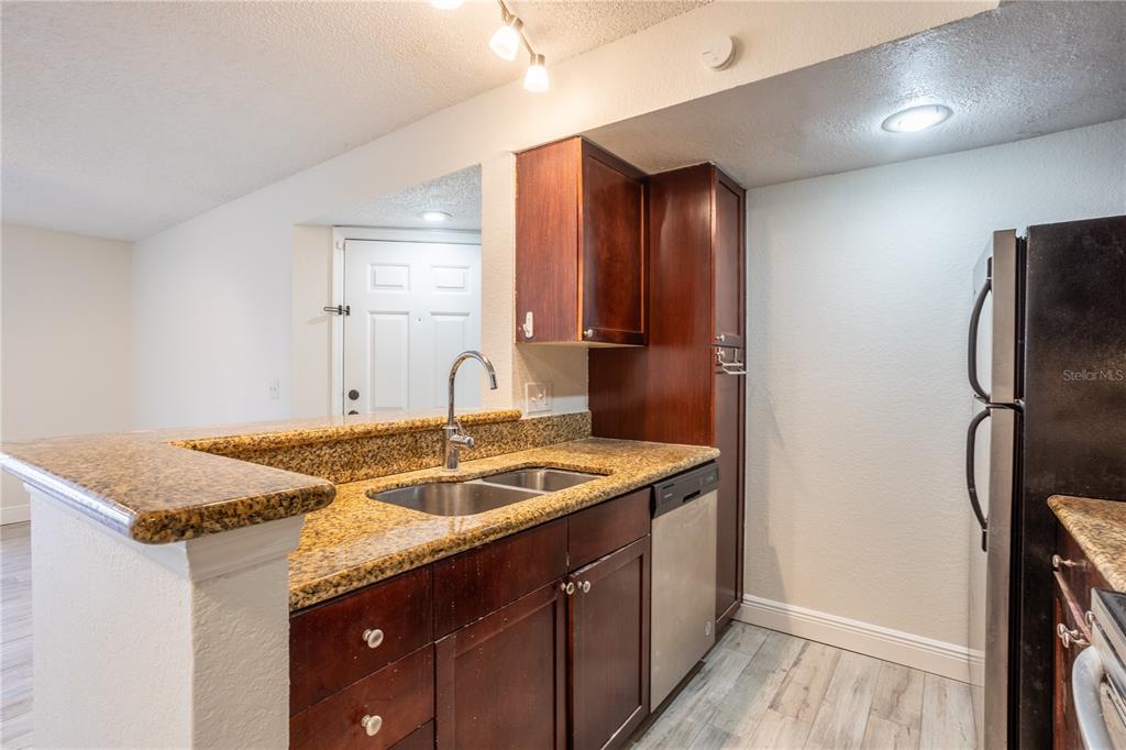 5156 Conroy Road, Unit 16 Orlando, FL 32811 - Photo 8 of 16 a kitchen with stainless steel appliances granite countertop a sink stove and refrigerator