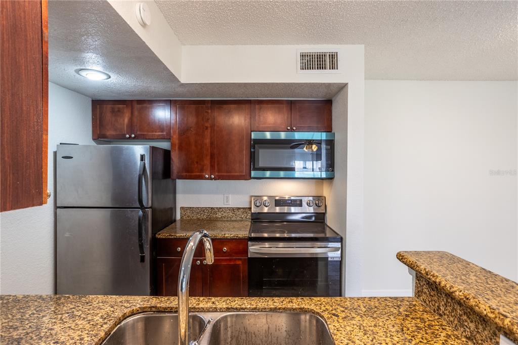 5156 Conroy Road, Unit 16 Orlando, FL 32811 - Photo 9 of 16 a kitchen with a refrigerator and a stove top oven