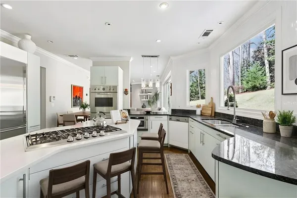 a kitchen with stainless steel appliances granite countertop a sink a stove and cabinets