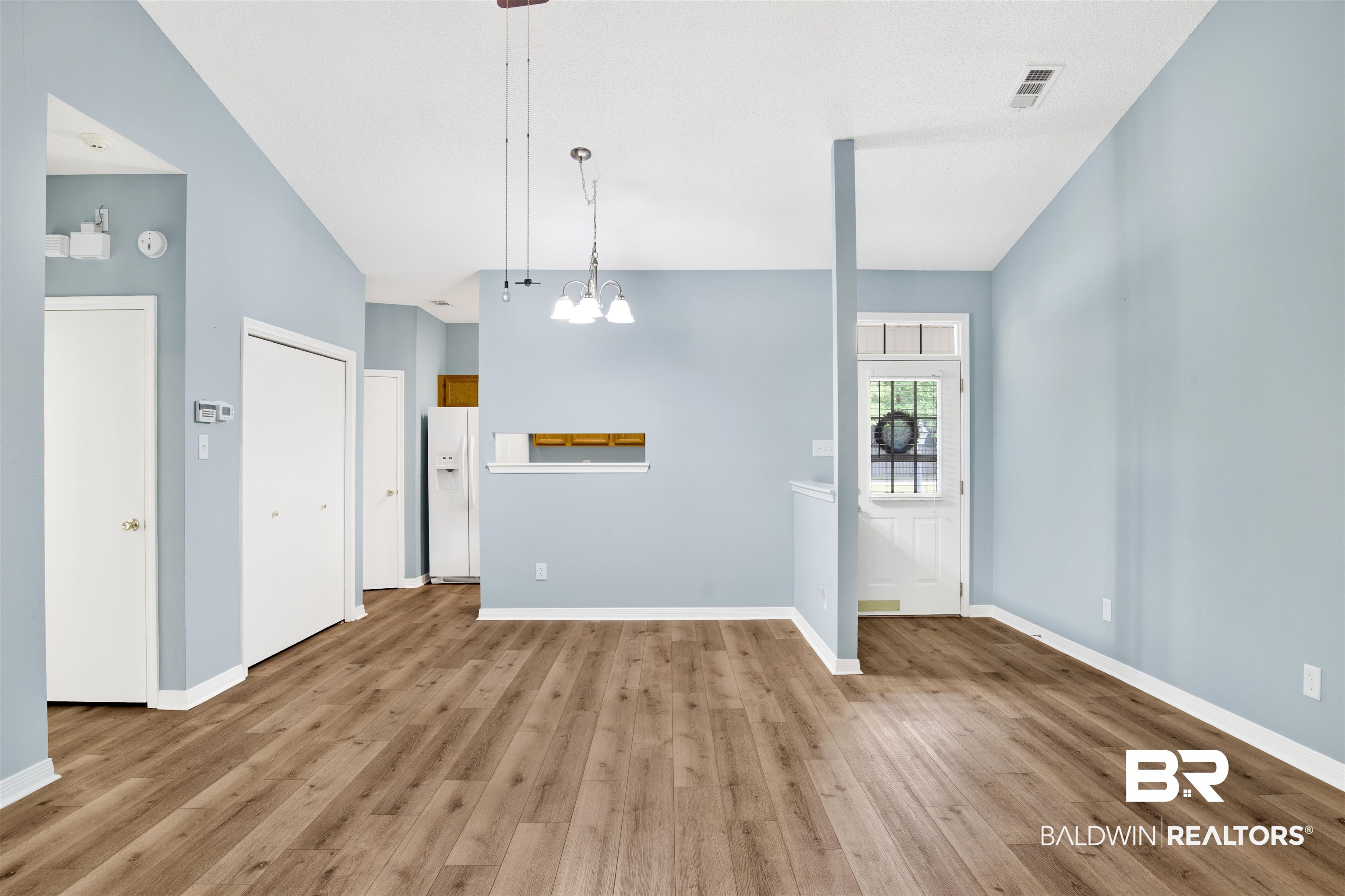 1258 Sutton Court, Unit 4 Mobile, AL 36609 - Photo 5 of 19 Unfurnished living room with an inviting chandelier, baseboards, light wood finished floors, and visible vents