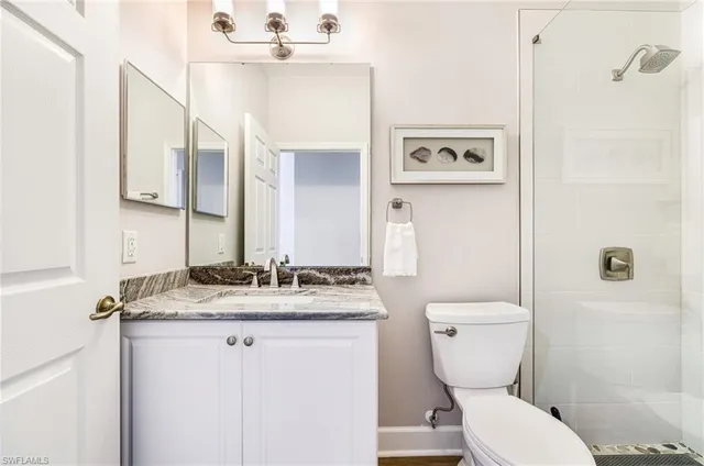a bathroom with a granite countertop sink mirror vanity and toilet