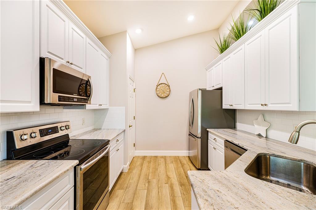 19081 Ridgepoint Drive, Unit 202 Estero, FL 33928 - Photo 6 of 50 a kitchen with stainless steel appliances a stove a sink a microwave and cabinets