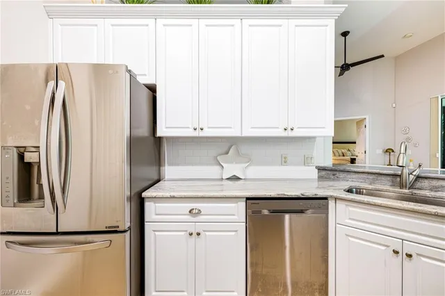 a kitchen with stainless steel appliances granite countertop a refrigerator sink and white cabinets