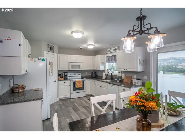 a kitchen with stainless steel appliances kitchen island granite countertop a stove top oven a sink a dining table and chairs