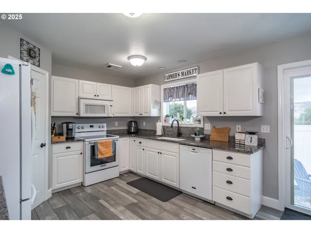 a kitchen with granite countertop white cabinets and white appliances