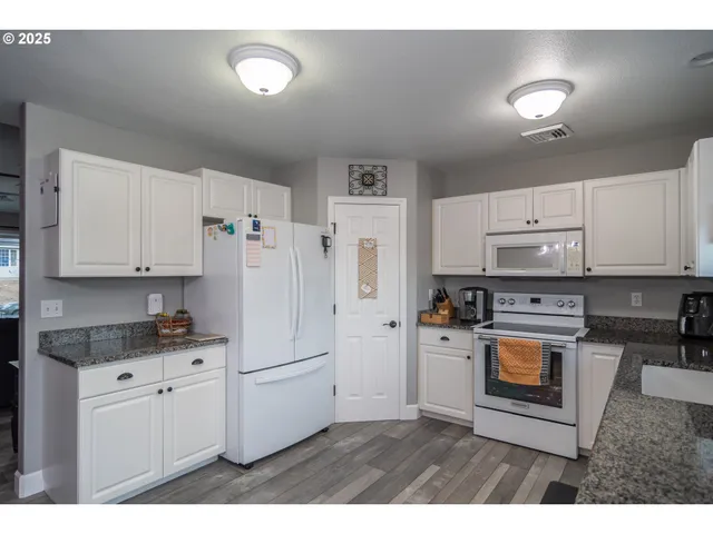 a kitchen with granite countertop a refrigerator stove and sink