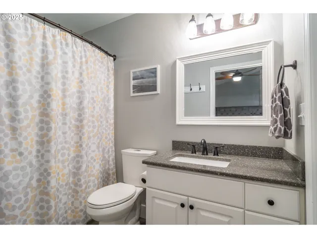 a bathroom with a granite countertop sink and a toilet