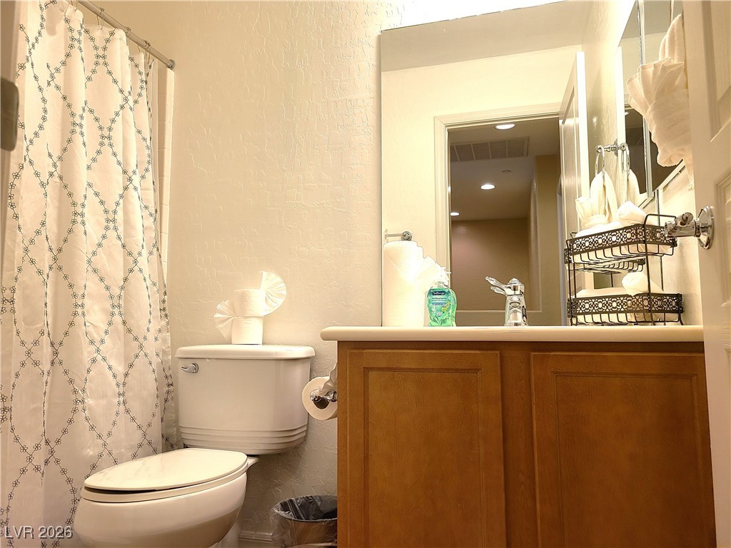 4650 Ranch House Road, Unit 70 North Las Vegas, NV 89031 - Photo 14 of 28 Full bathroom with a textured wall, toilet, vanity, and a shower with curtain