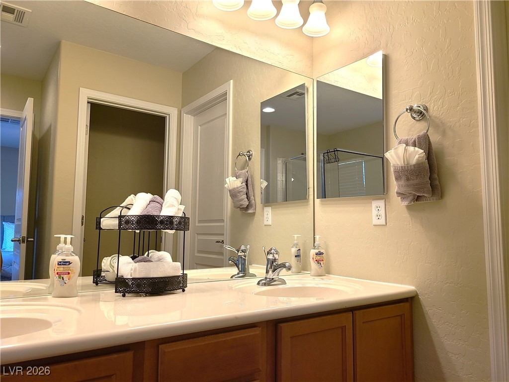 4650 Ranch House Road, Unit 70 North Las Vegas, NV 89031 - Photo 20 of 28 Bathroom featuring double vanity, a textured wall, and a shower with shower door
